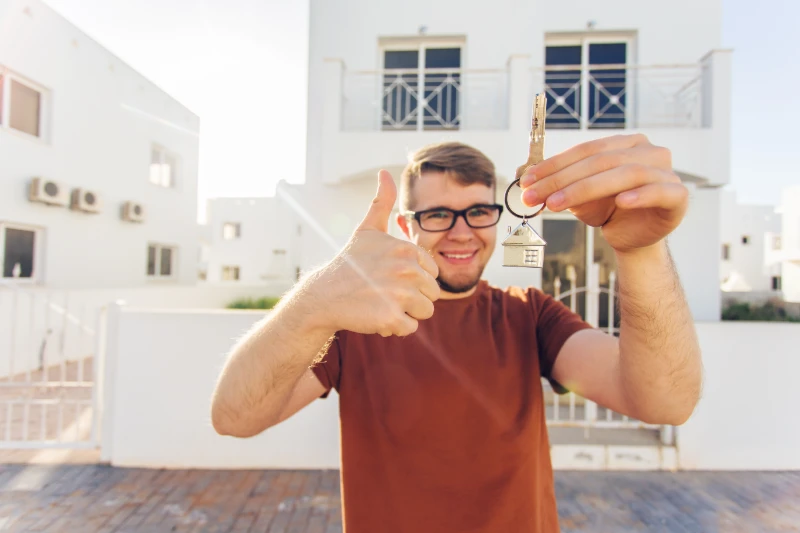 man-holding-key-outside-new-home